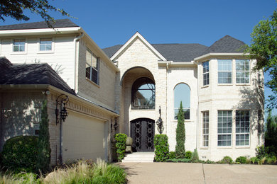 This is an example of a beige mediterranean two floor house exterior in Dallas with mixed cladding and a pitched roof.