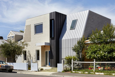 Cette photo montre une façade de maison multicolore tendance en brique de taille moyenne et à un étage avec un toit plat et un toit en métal.