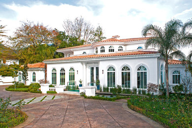Mid-sized tuscan white two-story stucco house exterior photo in Los Angeles with a hip roof and a tile roof