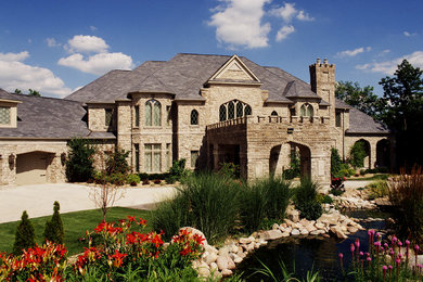 Photo of an expansive and beige mediterranean house exterior in Cedar Rapids with three floors and stone cladding.