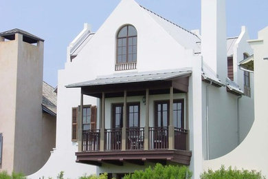 Diseño de fachada blanca mediterránea de tamaño medio de dos plantas con revestimiento de estuco y tejado a dos aguas