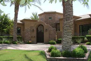 Large tuscan brown one-story stucco exterior home photo in Phoenix with a hip roof