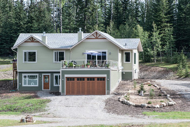Cette photo montre une grande façade de maison verte craftsman à un étage avec un revêtement en vinyle et un toit à croupette.