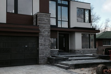 Cette image montre une façade de maison minimaliste en pierre de taille moyenne et à un étage avec un toit en métal.