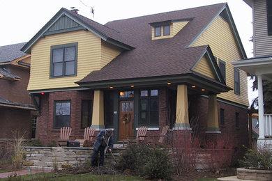 Diseño de fachada amarilla de estilo americano grande de dos plantas con tejado a dos aguas y revestimientos combinados