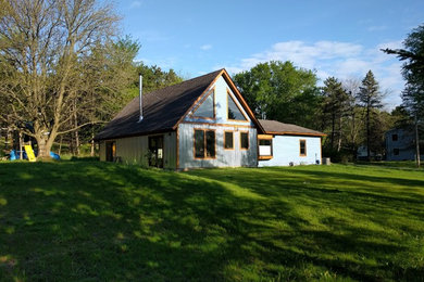 Modelo de fachada de casa azul rústica grande de dos plantas con revestimientos combinados, tejado a dos aguas y tejado de teja de madera