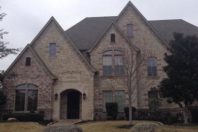 Huge traditional beige three-story stone exterior home idea in Dallas with a hip roof