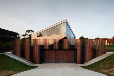 Cette photo montre une grande façade de maison tendance en bois à deux étages et plus avec un toit plat et un toit en métal.