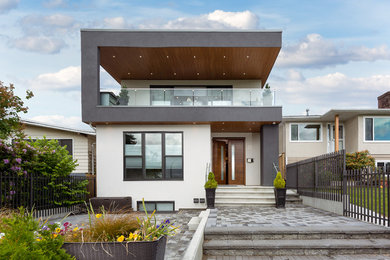 Example of a mid-sized trendy white two-story stucco exterior home design in Vancouver