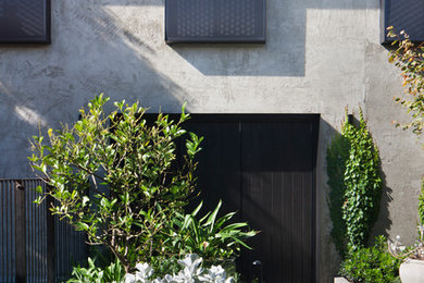Réalisation d'une façade de maison grise design en stuc de taille moyenne et à un étage avec un toit plat et un toit en métal.
