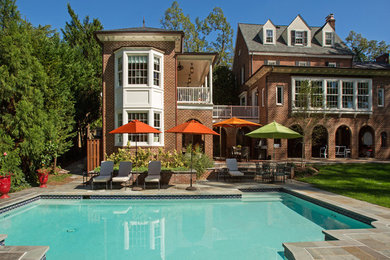 Example of a large classic red three-story brick house exterior design in DC Metro with a hip roof and a shingle roof