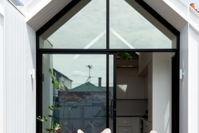Foto de fachada de casa blanca escandinava pequeña de una planta con revestimiento de aglomerado de cemento, tejado a dos aguas y tejado de metal