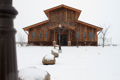 Ejemplo de fachada marrón rural grande de dos plantas con revestimiento de madera y tejado a dos aguas