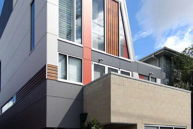 Photo of a small and gey contemporary house exterior in Other with three floors and concrete fibreboard cladding.