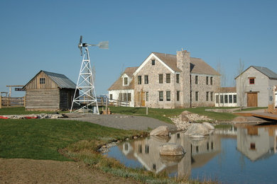 Inspiration for a large farmhouse three-story stone gable roof remodel in Other