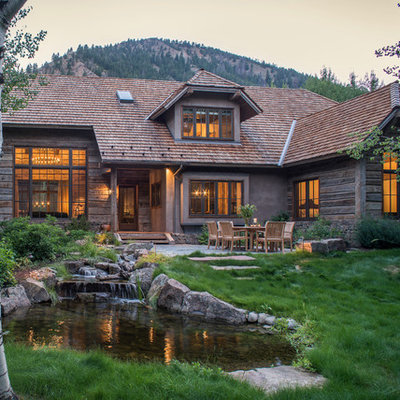 Mountain style brown wood exterior home photo in Other with a clipped gable roof