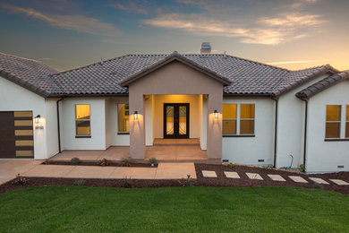 Modelo de fachada de casa blanca contemporánea de tamaño medio de una planta con revestimiento de estuco, tejado a cuatro aguas y tejado de teja de barro