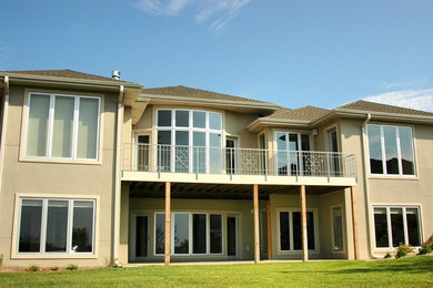 Example of a huge transitional beige two-story stucco house exterior design in Other with a hip roof and a shingle roof