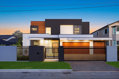 Cette photo montre une façade de maison moderne à un étage avec un revêtement mixte, un toit plat et un toit en métal.
