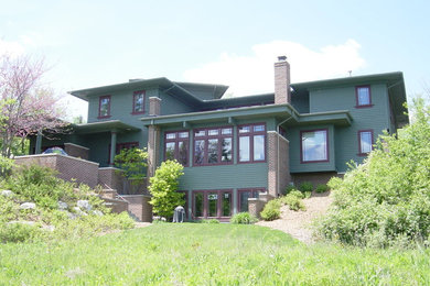 Diseño de fachada verde de estilo americano grande de tres plantas con revestimiento de vinilo y tejado a dos aguas