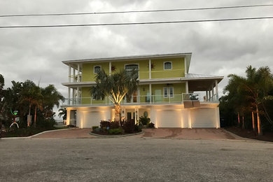 Esempio della facciata di una casa a schiera gialla contemporanea a tre piani di medie dimensioni con rivestimento in legno, tetto a padiglione e copertura in metallo o lamiera