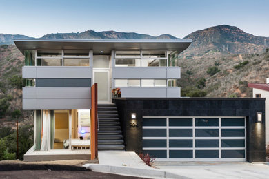 Mittelgroßes, Dreistöckiges Modernes Haus mit Metallfassade, grauer Fassadenfarbe und Pultdach