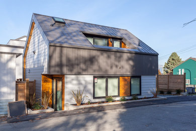 Exemple d'une petite façade de maison métallique et grise tendance à un étage avec un toit à deux pans et un toit en métal.