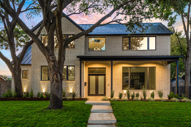 Mid-sized minimalist beige two-story brick house exterior photo in Dallas with a metal roof
