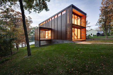 Immagine della villa piccola marrone moderna a tre piani con rivestimento in legno, tetto piano e copertura in metallo o lamiera