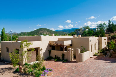 Inspiration for a mid-sized southwestern brown one-story adobe flat roof remodel in Albuquerque