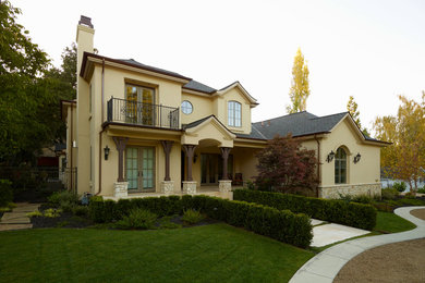 Foto de fachada beige clásica de tamaño medio de dos plantas con revestimiento de estuco y tejado a dos aguas