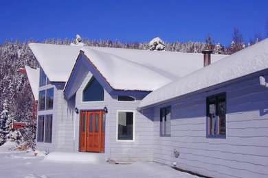 Modelo de fachada de casa azul clásica de tamaño medio de dos plantas con revestimiento de madera, tejado a dos aguas y tejado de teja de madera