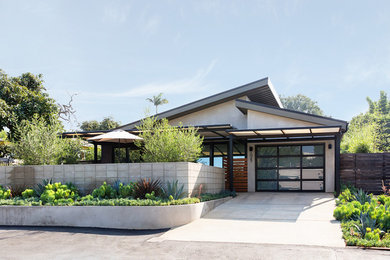 Modelo de fachada de casa beige actual de tamaño medio de una planta con revestimiento de estuco y tejado de metal