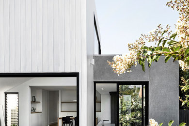 Photo of a medium sized and gey contemporary bungalow detached house in Melbourne with wood cladding, a pitched roof and a metal roof.