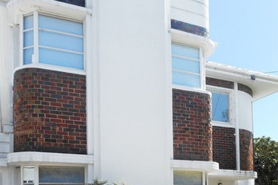 Foto de fachada de casa blanca retro de tamaño medio de dos plantas con revestimiento de ladrillo, tejado a cuatro aguas y tejado de teja de barro