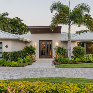 Example of an island style white one-story house exterior design in Miami with a hip roof and a metal roof