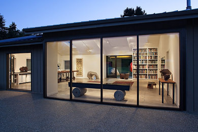 Modelo de fachada de casa gris contemporánea de tamaño medio de dos plantas con revestimiento de madera, tejado a dos aguas y tejado de metal