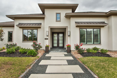 Example of a transitional gray stucco house exterior design in Houston with a shingle roof