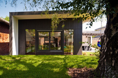 Inspiration pour une façade de maison noire design de plain-pied avec un revêtement mixte et un toit plat.