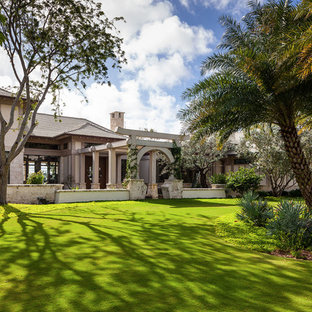 Large asian two-storey stucco beige house exterior in Miami with a gable roof and a shingle roof.