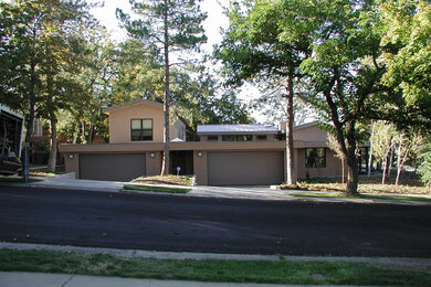 Cette photo montre une façade de maison beige tendance en stuc de taille moyenne et à un étage avec un toit à deux pans.