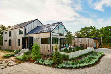 Modelo de fachada de casa contemporánea de dos plantas con revestimiento de madera, tejado a dos aguas y tejado de metal