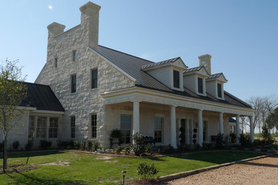 Large traditional white two-story stone exterior home idea in Houston with a metal roof