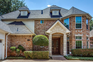 Large elegant beige two-story brick exterior home photo in Dallas with a shed roof