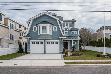 This is an example of a large and blue beach style detached house in Philadelphia with three floors, wood cladding, a mansard roof and a shingle roof.