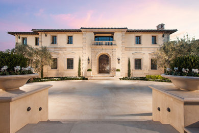 Example of a tuscan beige two-story stucco house exterior design in Orange County with a tile roof
