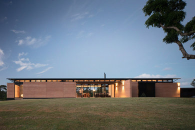Cette image montre une façade de maison multicolore design de taille moyenne et de plain-pied avec un toit plat et un toit en métal.