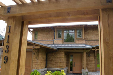 Imagen de fachada de casa marrón de estilo americano de tamaño medio de dos plantas con revestimiento de madera, tejado a cuatro aguas y tejado de metal