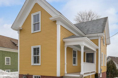 Ejemplo de fachada amarilla clásica de tamaño medio de dos plantas con revestimiento de madera y tejado a dos aguas
