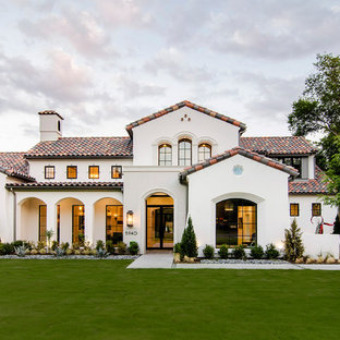 Beigefarbenes Mediterranes Haus mit Putzfassade und Satteldach in Dallas